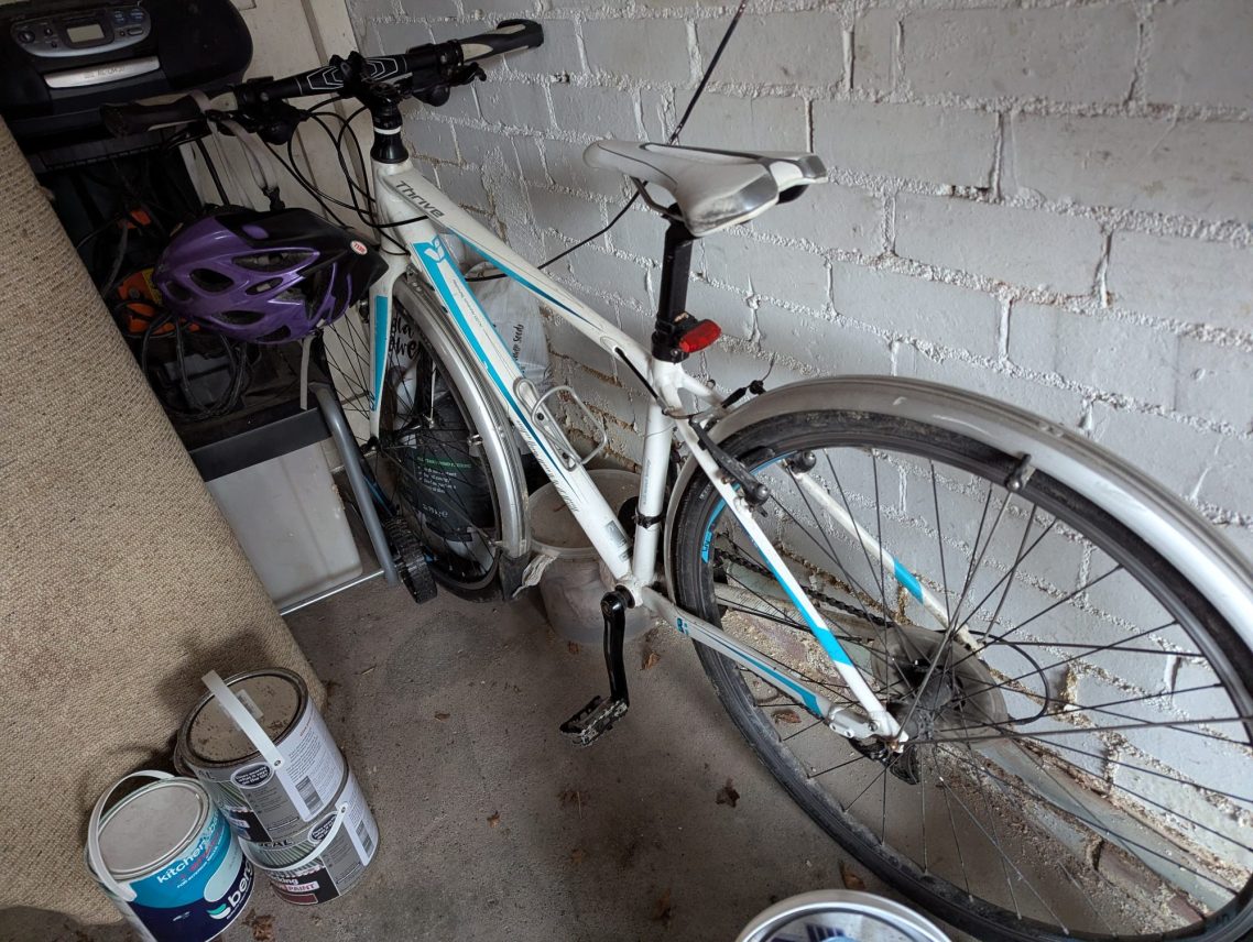 A neglected bike needn't stay that way! A white bike, sat in the corner a garage surrounded by paint cans, an old carpet and it's obviously rarely used.